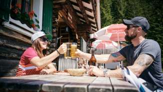 Zwei Personen stoßen mit Biergläsern vor der Gafadurahütte in den Liechtensteiner Alpen an
