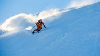 Marco Büchel fährt schwungvoll eine verschneite Piste in Malbun hinunter, Schnee wirbelt hinter ihm auf.
