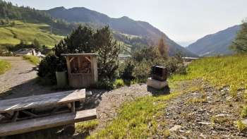 Grillplatz Schlucher-Treff mit Sitzbank, Feuerstelle und Blick ins Liechtensteiner Bergpanorama bei Sonnenschein