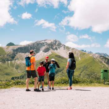 Familie mit Kindern genießt die Aussicht auf die Berge bei einer Falknerei-Wanderung.