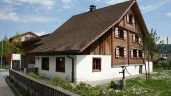 Historisches Küefer-Martis-Huus mit traditioneller Holzfassade und rotem Fensterläden in Ruggell, Liechtenstein.