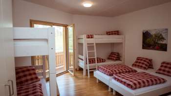 Familienfreundliches Mehrbettzimmer mit Etagenbetten und Einzelbetten im Gästehaus beim Camping Mittagsspitze.