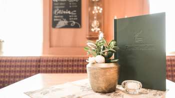 Detailaufnahme eines gedeckten Tisches mit Menükarten, Blumen und rustikaler Dekoration