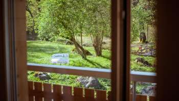 Blick vom Balkon des Gästehauses auf dem Campingplatz Mittagsspitze ins Grüne mit Bäumen und Liegewiese.