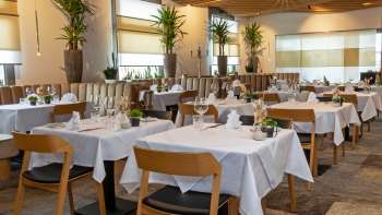 Blick in das stilvoll eingerichtete Restaurant Alpspitz mit weiß gedeckten Tischen und moderner, heller Atmosphäre.