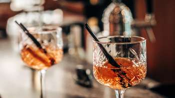 Zwei Aperitif-Gläser mit Orangenscheiben auf der Bar