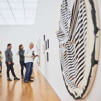 Besuchergruppe im Ausstellungsraum des Kunstmuseums, im Vordergrund ein großes, rundes Kunstwerk