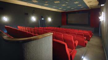 Seitlicher Blick in den Kinosaal des Alten Kino Vaduz mit roten Sesseln und atmosphärischer Beleuchtung.