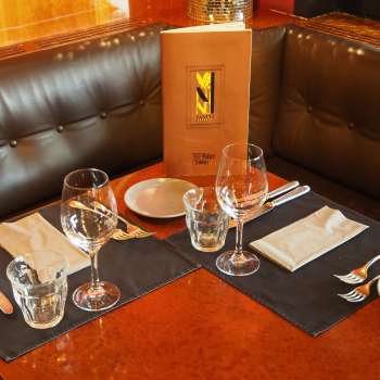 Gedeckter Tisch mit Speisekarte im Leder-Sitzbereich des Vanini Cafés