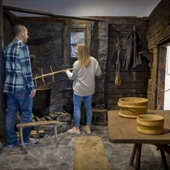 Besucher erkunden eine alte Rauchküche im Walsermuseum Triesenberg