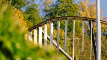Nahaufnahme des gewölbten Metallbogens mit vertikalen Lamellen des Centrum für Kunst vor herbstlicher Waldkulisse in Vaduz.