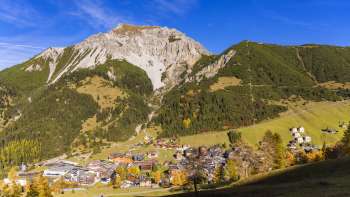 Blick auf das Bergdorf Malbun in Liechtenstein mit umliegender Berglandschaft bei klarem Himmel.