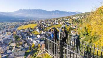 Wanderer am Geländer des Aussichtspunktes Känzile mit Panoramaausblick auf Vaduz und die umliegenden Berge.