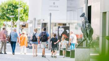 Menschen spazieren durch die moderne Fussgängerzone von Vaduz vorbei am Kunstmuseum