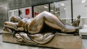 Üppige Frauenfigur aus Bronze – das Kunstwerk „Reclining Woman“ von Fernando Botero als Blickfang in der Innenstadt.