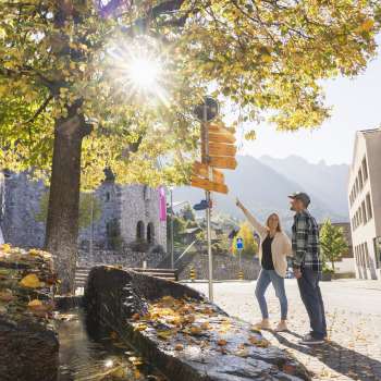 Herbstliche Szene mit Wanderweg-Wegweiser im Ortszentrum von Triesenberg