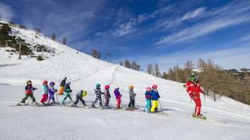 Skilehrer im Malbi-Park Malbun motiviert Kinder auf dem Übungshang – perfekte Umgebung für die ersten Schwünge im Schnee