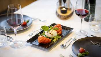 Ein weiterer Blick auf den gedeckten Tisch, mit Fokus auf die modernen schwarzen Teller und die Speisen in der Mitte.