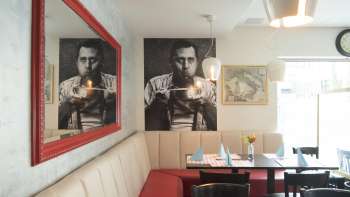 Gemütliche Sitzecke im Restaurant Made in Italy mit stilvollem Wandbild und rotem Spiegel.