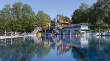 Blick auf das große Schwimmbecken mit bunter Rutschenlandschaft im Schwimmbad Mühleholz in Liechtenstein. Blick auf das große Schwimmbecken mit bunter Rutschenlandschaft im Schwimmbad Mühleholz in Liechtenstein.