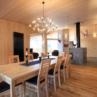 Helles Holzinterieur mit Esstisch und Kamin im Haus Ochsenkopf in Malbun, Liechtenstein