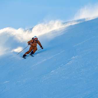 Marco Büchel fährt schwungvoll eine verschneite Piste in Malbun hinunter, Schnee wirbelt hinter ihm auf.